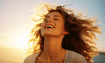 A joyful woman laughing against a sunset backdrop, symbolizing powerful life lessons about happiness and living fully.